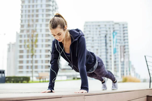 都会の中で屋外で板運動をする若い女性にフィット — ストック写真