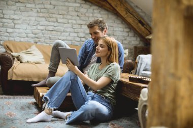 Birlikte otururken dijital tablet kullanan mutlu çift.