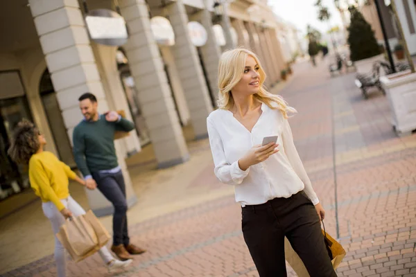 Όμορφη Γυναίκα Χάρτινη Τσάντα Ψώνια Χρησιμοποιώντας Κινητό Τηλέφωνο Ενώ Περπάτημα — Φωτογραφία Αρχείου