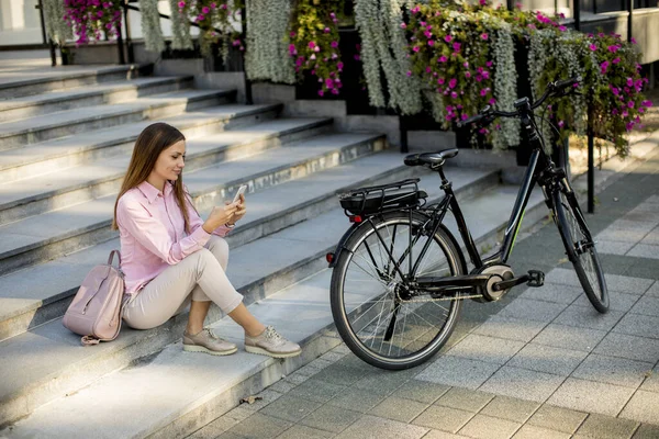 Młoda Kobieta Siedzi Schodach Przy Rowerze Używa Smartfona Świeżym Powietrzu — Zdjęcie stockowe