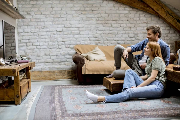 Smiling lovely young couple relaxing and watching TV at rustic home