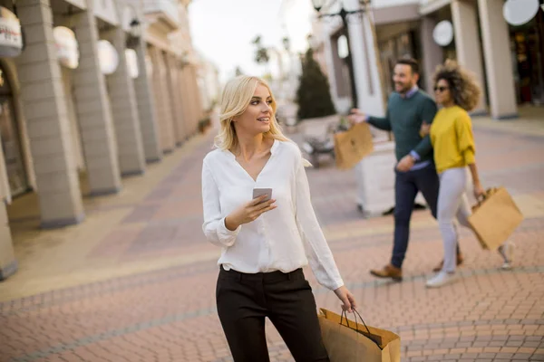 Beautiful Woman Paper Shopping Bag Using Mobile Phone While Walking — Stok fotoğraf