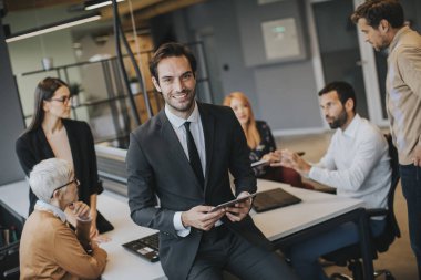 Young businessman using digital tablet in office in front of his team