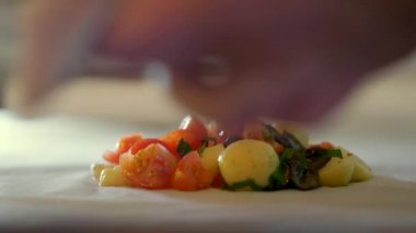 Profesyonel şef salataya yaldızlı balık parçaları koyuyor.