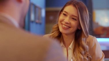 Genç çift restoranda kırmızı şarap kadehleriyle yemek yiyor.