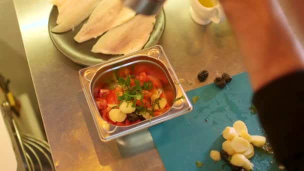 Chef prepara batatas, tomates, salsa e azeitonas no conselho no prato metálico profissional na cozinha — Vídeo de Stock