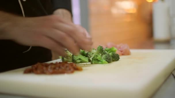 Chef prepares broccoli with dried tomatoes and chopped turkey meat on the table — Stock Video