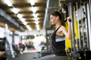 Güzel genç bir kadın spor salonunda müzik dinlerken egzersiz yapıyor.