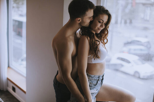 Affectionate young couple standingby the window in the room of the apartment