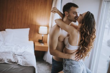 Sevecen genç bir çift. Dairenin penceresinin önünde duruyorlar.