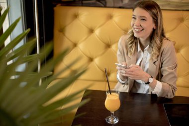 Cafe 'de cep telefonu kullanan çekici bir kadın.