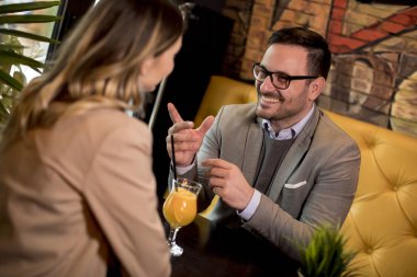 Kafede oturup portakal suyu içen sevimli genç bir çift.