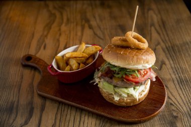 Ev yapımı pizza hamurlu çörek, eritilmiş çedar peyniri, pastırma, domates, roket, soğan halkalı marul ve baharatlı patates kızartması.