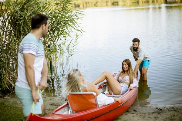 Hombres Jóvenes Guapos Tirando Canoa Con Mujeres Jóvenes Lago Tranquilo — Foto de Stock