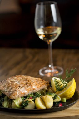 Izgara patatesli somon fileto, masada pırasa ve ıspanak ile beyaz şarap.