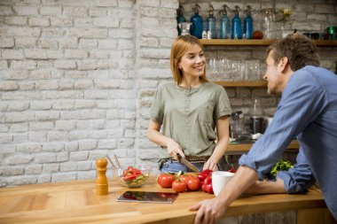 Genç bir kadın kırsal mutfakta kahve içerken yemek pişiriyor.