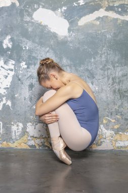 Sivri uçlu ayakkabılı genç balerin kirli duvarın yanında.