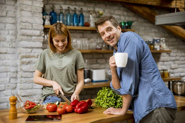 Jovem Cozinhando Enquanto Homem Bebe Café Cozinha Rústica — Fotografia de Stock