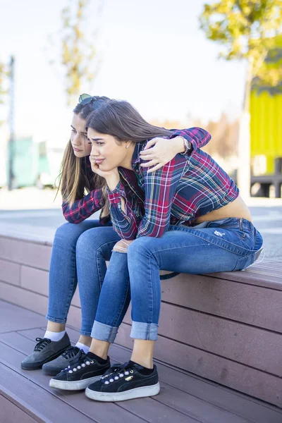 Young woman comforts a sad female friend in the park