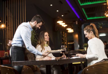 Restoranda yemek servisi yapan iki gülümseyen genç bayan arkadaş.