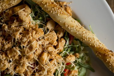 Roketli tavuk salatası, kiraz domatesleri, füme peynir ve çıtır susamlı çubuklar.