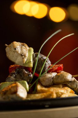 Sebzeli tavuk, domuz eti ve biftek şişleri ve masada baharatlı patates.