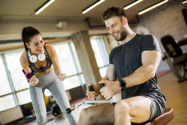 Stilig Ung Man Med Sittande Radmaskin Gymmet Med Stöd Kvinnlig — Stockfoto