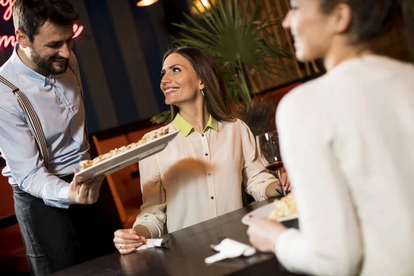 Dos Jóvenes Amigas Sonrientes Restaurante Con Camarero Sirviendo Cena —  Fotos de Stock