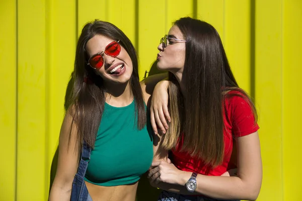 Duas Mulheres Jovens Casuais Bonitos Brincando Frente Parede Amarela — Fotografia de Stock
