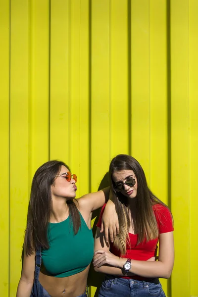 Dwie Słodkie Przypadkowe Młode Kobiety Zabawiające Się Przed Żółtą Ścianą — Zdjęcie stockowe