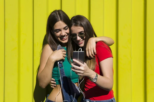 Yeşil Duvara Karşı Mutlu Yüzlü Genç Kadınlar Kulaklıkla Müzik Dinleyip — Stok fotoğraf