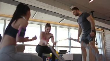 Güzel genç bayan spor salonunda savaş halatlarıyla pratik yapıyor.
