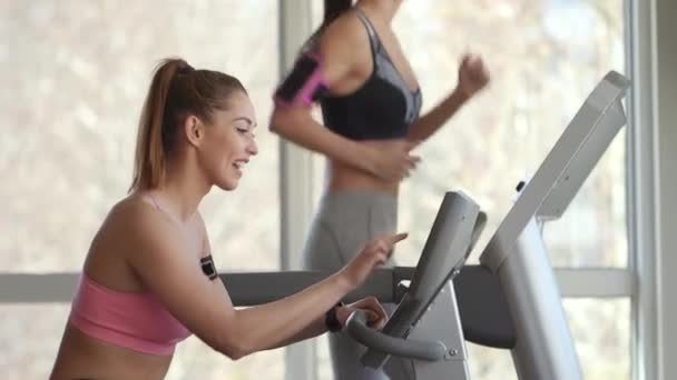 Jolie jeune femme utilisant tapis roulant dans la salle de gym moderne — Video