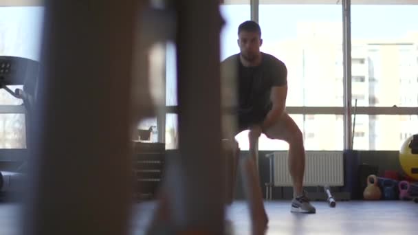 Handsome young man practicing with battle ropes in the gym — Stock Video