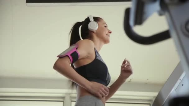 Mooie jonge vrouw met behulp van loopband in moderne sportschool — Stockvideo