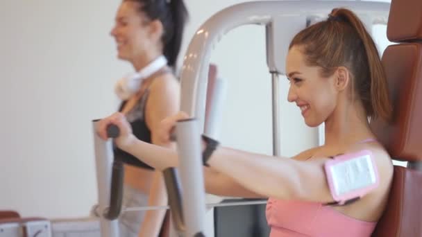Junge Frau trainiert Brustgymnastik an einem Gerät im Fitnessstudio — Stockvideo