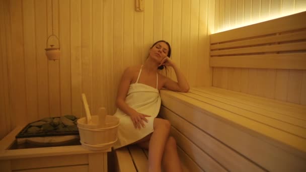 Красивая молодая женщина отдыхает в сауне — стоковое видео