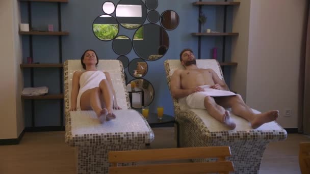 Jeune couple couché sur les lits de tepidarium dans le spa — Video