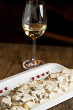 Krem mantar soslu rendelenmiş gnocchi soslu tavuk eti ve masada beyaz şaraplı füme peynir.