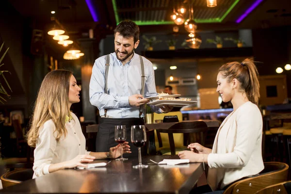 Deux Jeunes Amies Souriantes Dans Restaurant Avec Serveur Servant Dîner — Photo