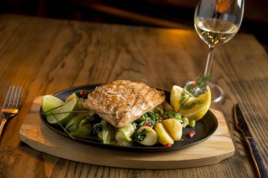 Izgara patatesli somon fileto, masada pırasa ve ıspanak ile beyaz şarap.