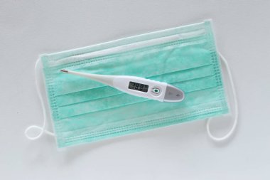 Masada cerrahi kulak ilmiği maskesi ve termometre var.