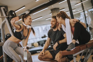 Spor kıyafetli bir grup genç spor salonunda cep telefonuyla selfie çekiyor.