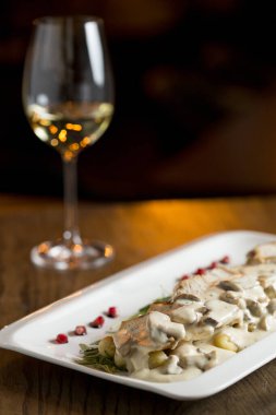 Krem mantar soslu rendelenmiş gnocchi soslu tavuk eti ve masada beyaz şaraplı füme peynir.