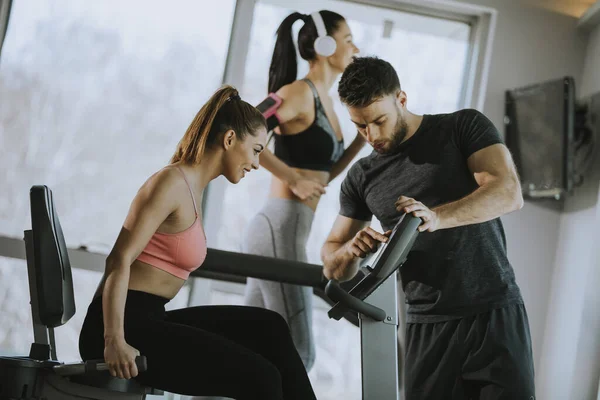 Personlig Tränare Med Söt Ung Kvinna Cykel Maskin Gymmet — Stockfoto