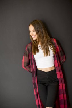 Duvarın yanında duran güzel, gülümseyen, uzun saçlı genç kadına bakın.