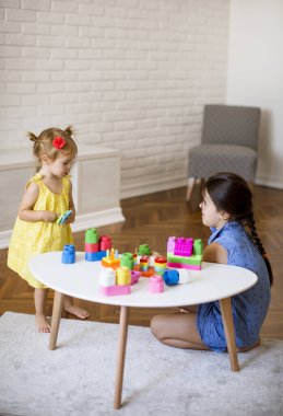 İki küçük tatlı kız masadaki bloklarla oynuyorlar.