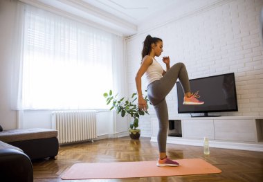 Evde egzersiz yapan sevimli, genç ve çekici bir kadın.