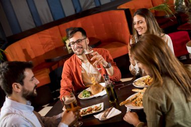 Bir grup genç restoranda yemek yiyor.