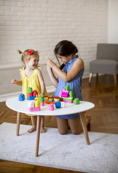 两个可爱的小女孩在房间的桌子边玩木块 — 图库照片